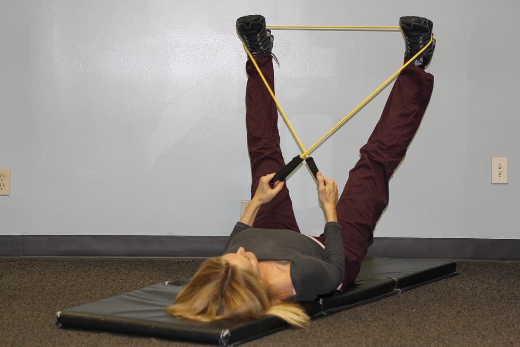 Physiotherapist guiding a patient through hip muscle strengthening exercises with resistance bands